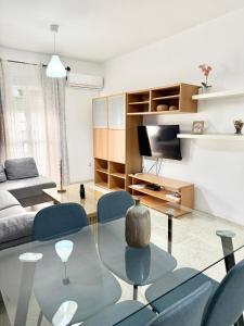 a living room with a glass table and blue chairs at Apartamento entero a 10 minutos en coche de Sevilla Centro in Camas