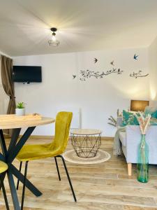 a living room with a table and birds on the wall at Le Nid Marin in Ault