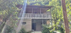 a building with a balcony in the middle of a forest at Medo Guesthouse in Khashiti