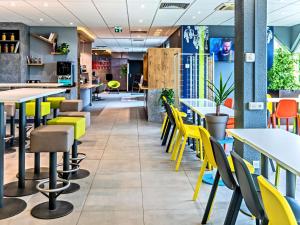 un restaurante con mesas y sillas amarillas en ibis budget Strasbourg Sud Illkirch, en Geispolsheim