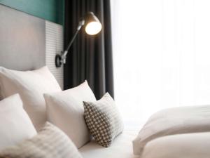 a bedroom with white pillows and a bed with a lamp at Mercure Hannover Oldenburger Allee in Hannover