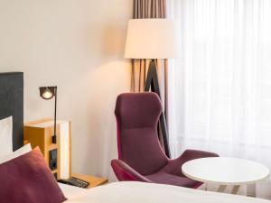 a hotel room with a chair and a table at Mercure Hannover Oldenburger Allee in Hannover +81 photos