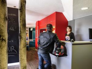 a man standing at a counter in front of a woman at hotelF1 Lyon Saint Priest in Saint-Priest