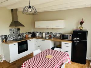 a kitchen with a table and a black refrigerator at Le Petit Bréhémontais in Bréhémont