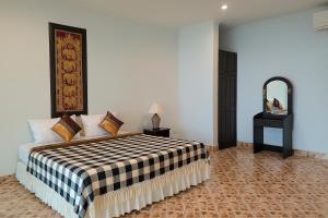 una camera da letto con un letto con una coperta a quadri di Kamala Orchid Guesthouse a Kamala Beach