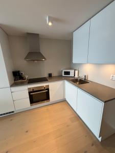 a kitchen with white cabinets and a sink at Ny leilighet i Ålesund med fantastisk utsikt in Ålesund