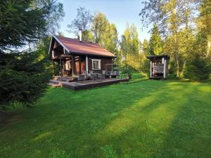 a small cabin in a yard with a green lawn at Ainja Puhkemaja in Viljandi