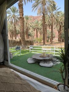 una camera con finestra, tavolo e palme di caravan alula a Al Ula