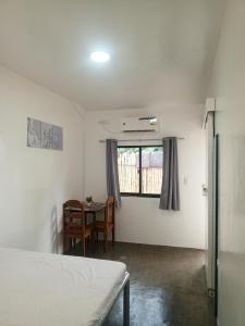 Un dormitorio con una cama y una mesa y una ventana. en Joan&Jimboy, en General Luna