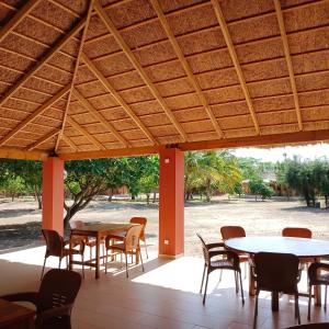 a patio with tables and chairs under a wooden roof at JAMNAATI Campement in Mboro