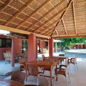a patio with tables and chairs under a wooden ceiling at JAMNAATI Campement in Mboro