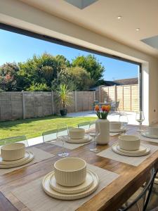a wooden table with plates and wine glasses on it at The Crescent Villa Lancing in Lancing