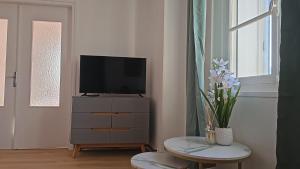 a living room with a television and a table with flowers at Appartement de 50 M2 avec cuisine neuve plus terrasse de 40 m2 in Le Portel +6 photos