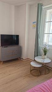 a living room with a tv and a table and a couch at Appartement de 50 M2 avec cuisine neuve plus terrasse de 40 m2 in Le Portel