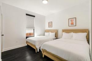 two beds in a bedroom with white walls and wood floors at Venus Rooftop Villa in New Orleans +8 photos