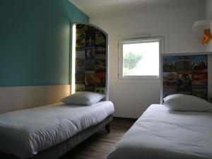 Dos camas en una habitación con ventana. en hotelF1 Orange Centre Echangeur A7 A9, en Orange