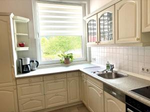 a kitchen with white cabinets and a sink and a window at Gartenidylle in Amelinghausen