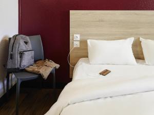 a bedroom with a bed and a backpack on a chair at hotelF1 Rouen Zénith Parc Expo in Saint-Étienne-du-Rouvray