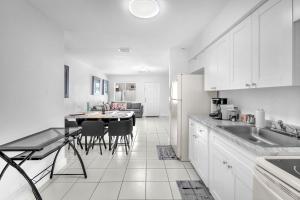 a kitchen with white cabinets and a table with chairs at Costerra Miami 2BR in Miami +25 photos