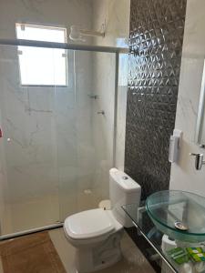 a bathroom with a toilet and a glass sink at chalé vista para montanha in Penedo