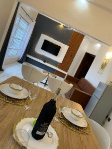 a wooden table with plates and wine glasses on it at Villa de 3 appartements in Porto-Novo
