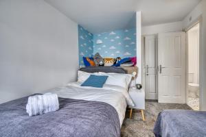 a bedroom with two beds and a blue wall at Comfort Lettings - 4 bedroom, 8 Beds & 2 Free Parking, Garden, Family and Workers Friendly in Market Harborough