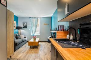 a kitchen and living room with blue walls and a couch at OFFRE octobre Le Cosy Studio, idéal pro ou couple, proche de la plage in Le Havre