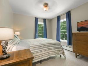 a bedroom with a bed and a dresser and windows at Killington Terrace Lodge - Spacious 5BR Killington Home with 2 Kitchens, Game Room & Pet Friendly in Sherburne Center