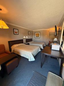 a hotel room with two beds and a desk at Motel Au Bercail in Temiscaming