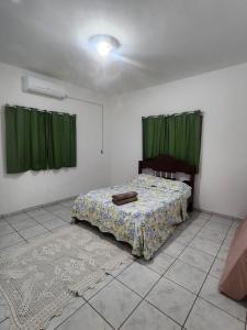 Schlafzimmer mit einem Bett mit grünen Vorhängen und einem Teppich in der Unterkunft casa verde hospedaria in Goiás