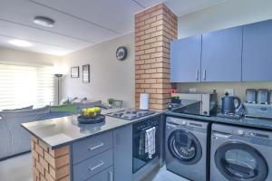 a kitchen with a stove and washing machines at Waterfall Ridge Luxurious Apartments - Backup Power! in Midrand