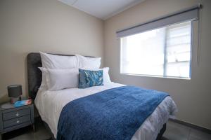 a bedroom with a bed with a blue blanket and a window at Waterfall Ridge Luxurious Apartments - Backup Power! in Midrand +25 photos