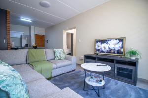 a living room with a couch and a tv at Waterfall Ridge Luxurious Apartments - Backup Power! in Midrand