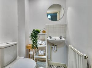 a bathroom with a sink and a toilet and a mirror at Comfort Lettings - 4 bedroom, 8 Beds & 2 Free Parking, Garden, Family and Workers Friendly in Market Harborough +34 photos