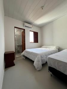 a bedroom with two beds and a bathroom with a window at Casa de Praia - Francês/Marechal Deodoro in Marechal Deodoro