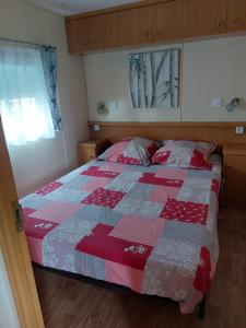a bedroom with a bed with a red and gray quilt at Au refuge de Lahontan in Castelnau-dʼAuzan
