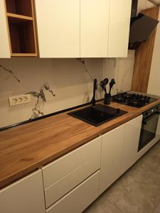 a kitchen with white cabinets and a sink at Family's delight in Giroc