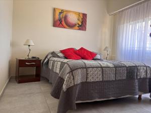 una camera da letto con un letto con cuscini rossi di La Casita del Golf a Sierra de la Ventana Altre 33 foto