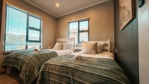 two beds in a room with two windows at Kleine Krantzie in Wilderness