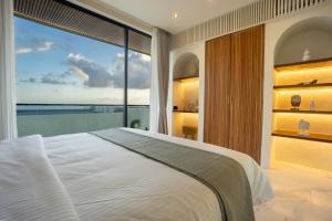 a bedroom with a large white bed and a large window at White Residence by Iji in Uluwatu