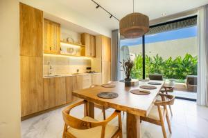 a dining room with a wooden table and chairs at White Residence by Iji in Uluwatu
