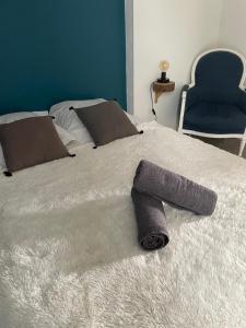 a bed with a towel on it with a blue chair at MOINES - Centre historique de charme in Vannes +14 photos