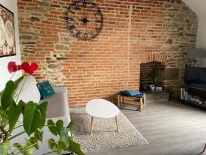 a living room with a brick wall with a clock at MOINES - Centre historique de charme in Vannes