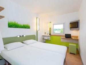 a bedroom with a large white bed and a television at Ibis Budget Angers Parc des Expositions in Saint-Sylvain-dʼAnjou +73 photos