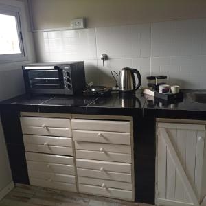 a kitchen with a black counter top with a microwave at El Refugio Tapalque in Tapalqué +3 photos