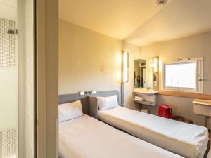 a room with two beds and a sink and a window at ibis budget Bourges in Bourges