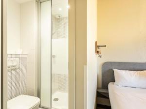 a bathroom with a shower and a toilet and a bed at ibis budget Bourges in Bourges