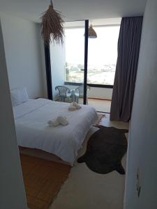 a bedroom with a bed and a large window at SURFLAND APPARTEMENTS Vue sur mer Pour les familles in Oualidia