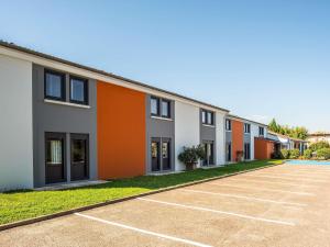 an empty parking lot in front of a row of houses at Ibis Budget Villefranche in Limas