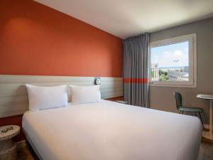 a bedroom with a large white bed and a window at ibis budget Nice Aeroport in Nice